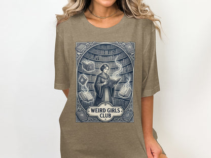 T-shirt graphic of a woman reading in a library with "Weird Girls Club" text.