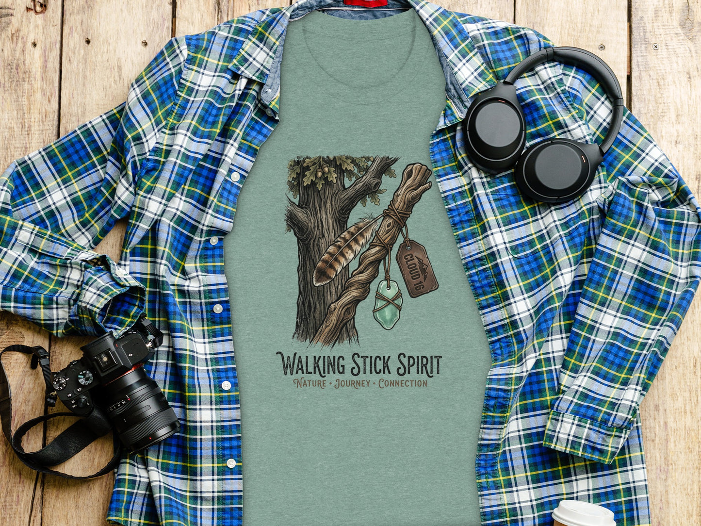 Heritage Walking Stick Spirit: Journey Nomad Tee: T-shirt with "Walking Stick Spirit" logo of tree and feather on wooden background.