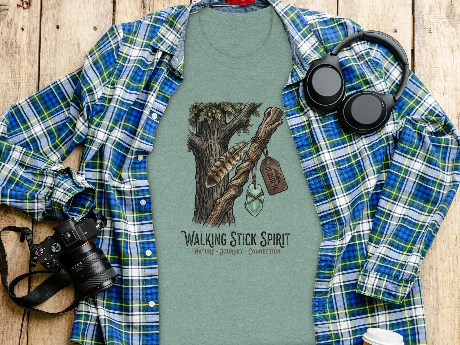 Heritage Walking Stick Spirit: Journey Nomad Tee: T-shirt with "Walking Stick Spirit" logo of tree and feather on wooden background.