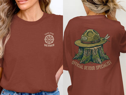 Front: Take the 16 detour logo. Back: Park Ranger hat on stump with dragonfly, official detour specialist.