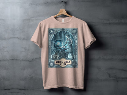 T-shirt with a graphic of a woman blacksmith and cat, "Weird Girls Club" text.