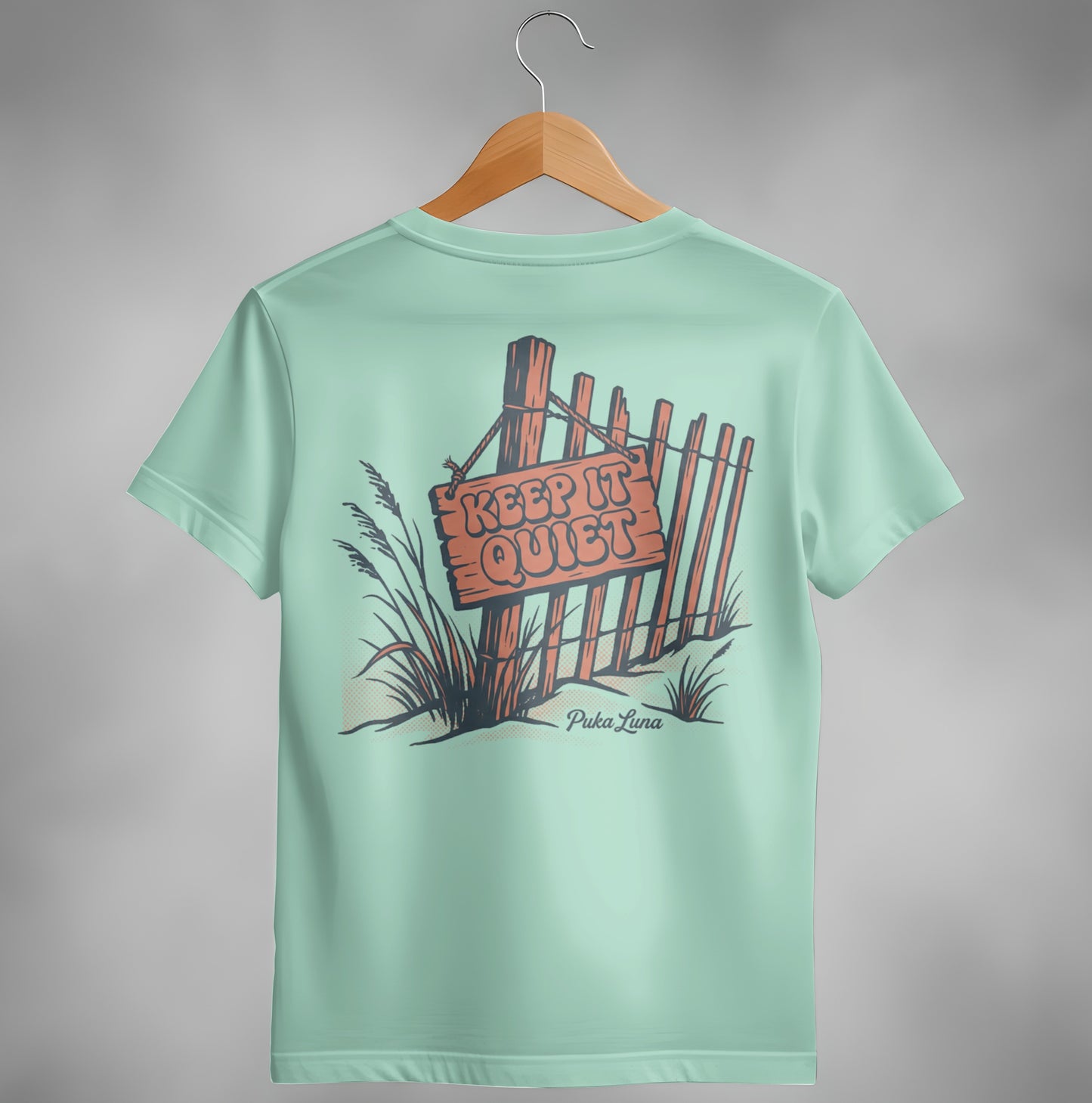 Pale blue t-shirt with a wooden fence and "Keep It Quiet" sign graphic.
