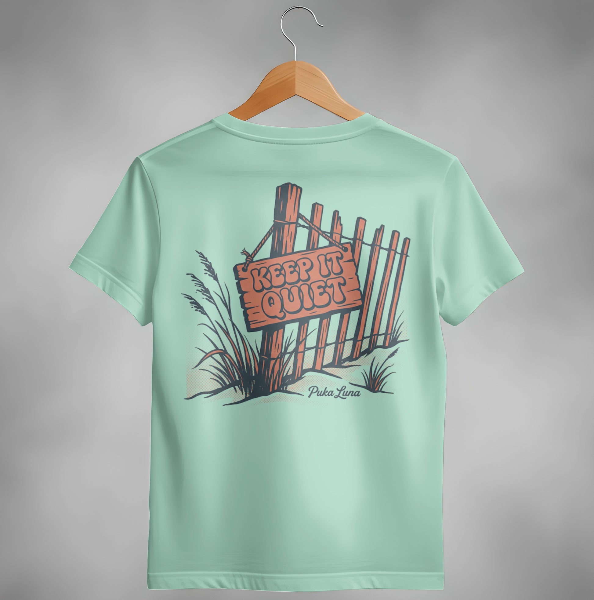 Pale blue t-shirt with a wooden fence and "Keep It Quiet" sign graphic.