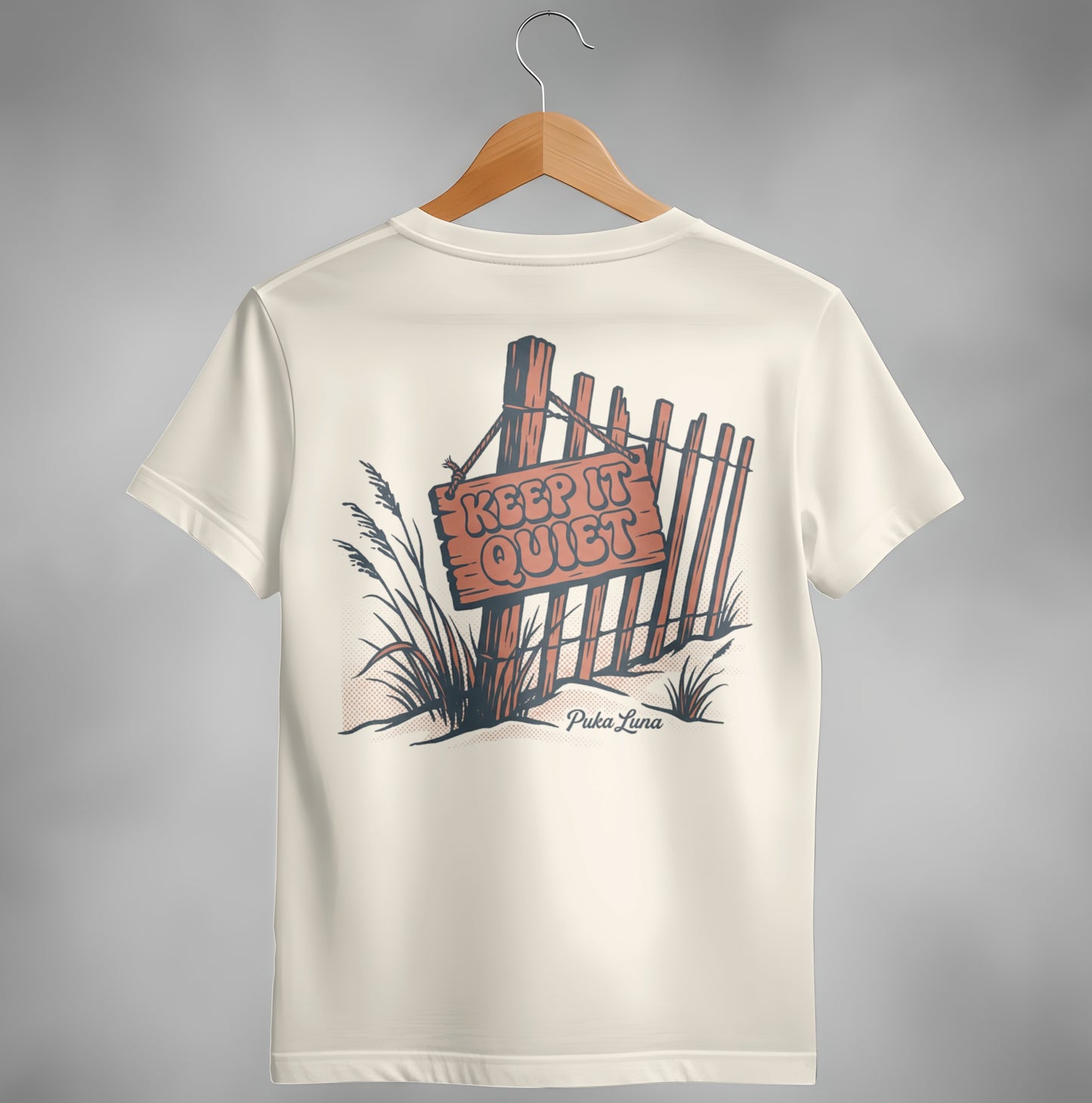 Cream t-shirt with "KEEP IT QUIET" sign on a wooden fence illustration.