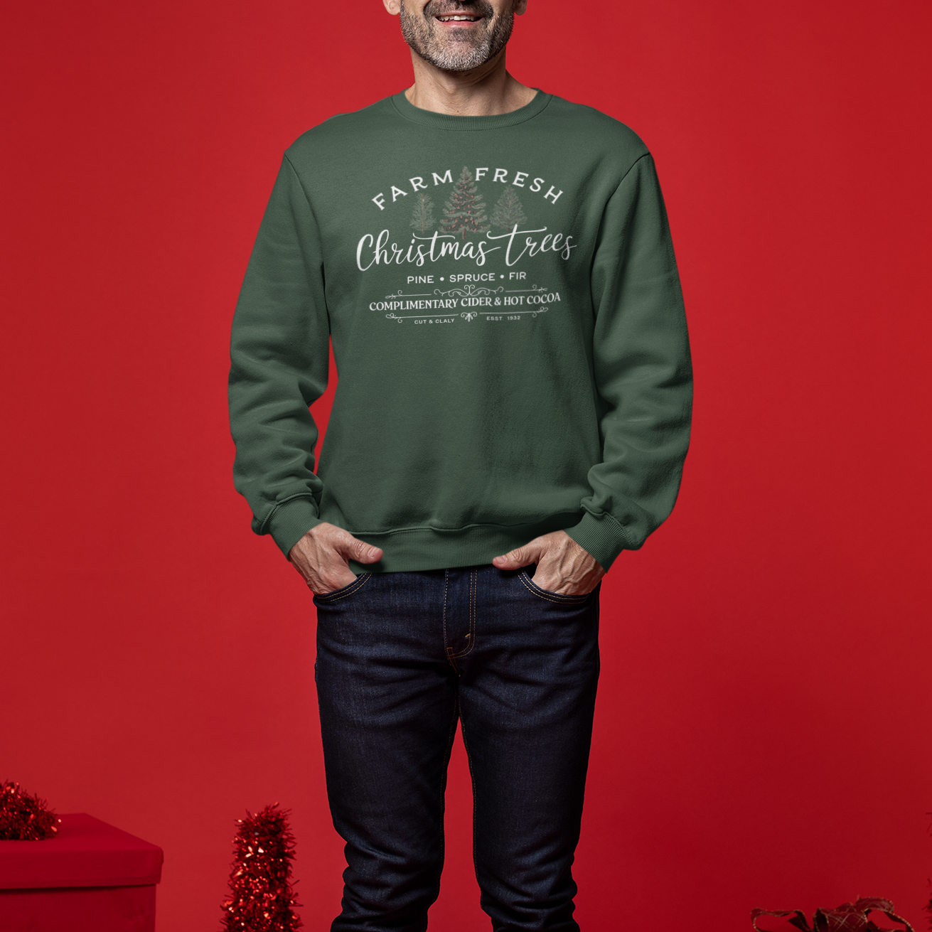 Man wearing a green sweatshirt with text, standing against a red background with Christmas decorations.