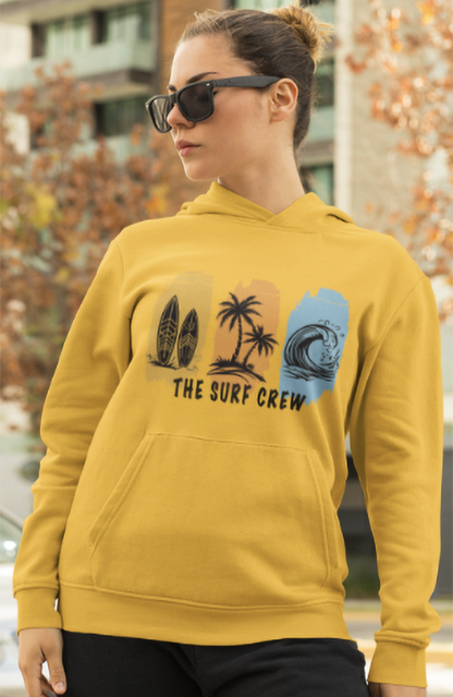 Person wearing a mustard yellow hoodie with 'The Surf Crew' design outdoors.