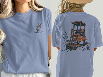 Blue t-shirt with Puka Luna design on front and lifeguard stand graphic on back.
