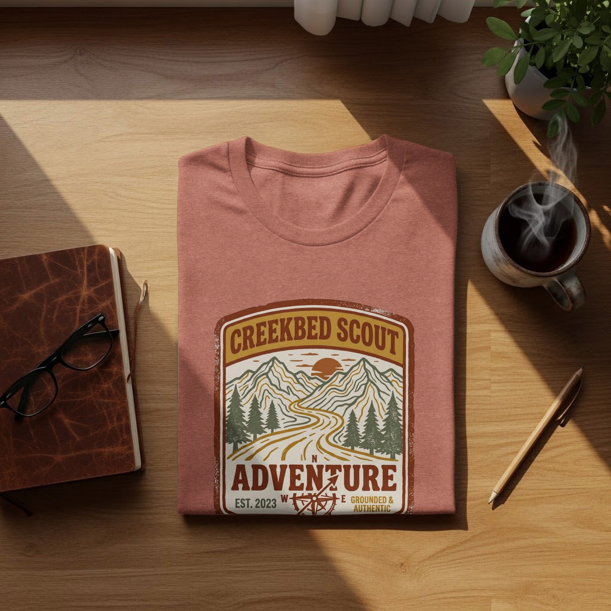 Rugged Creekbed Scout Adventure Emblem Wilderness Shirt: Creekbed Scout t-shirt with mountain road graphic, "Est. 2023."