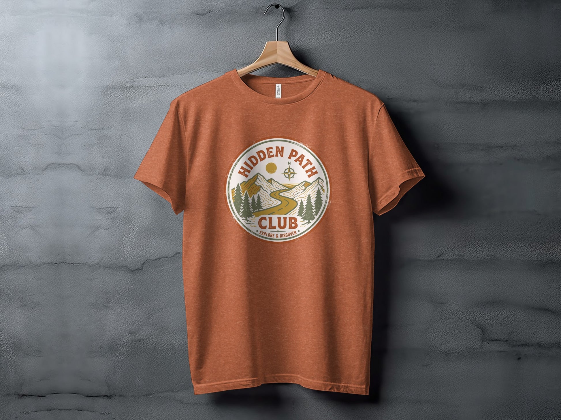 Rugged Hidden Path Club Explorer Wilderness Shirt: Orange t-shirt with "Hidden Path Club" circular logo featuring mountains and compass.