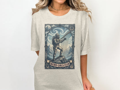 Astronaut playing a harp in a mountain landscape with "Weird Girls Club" banner.
