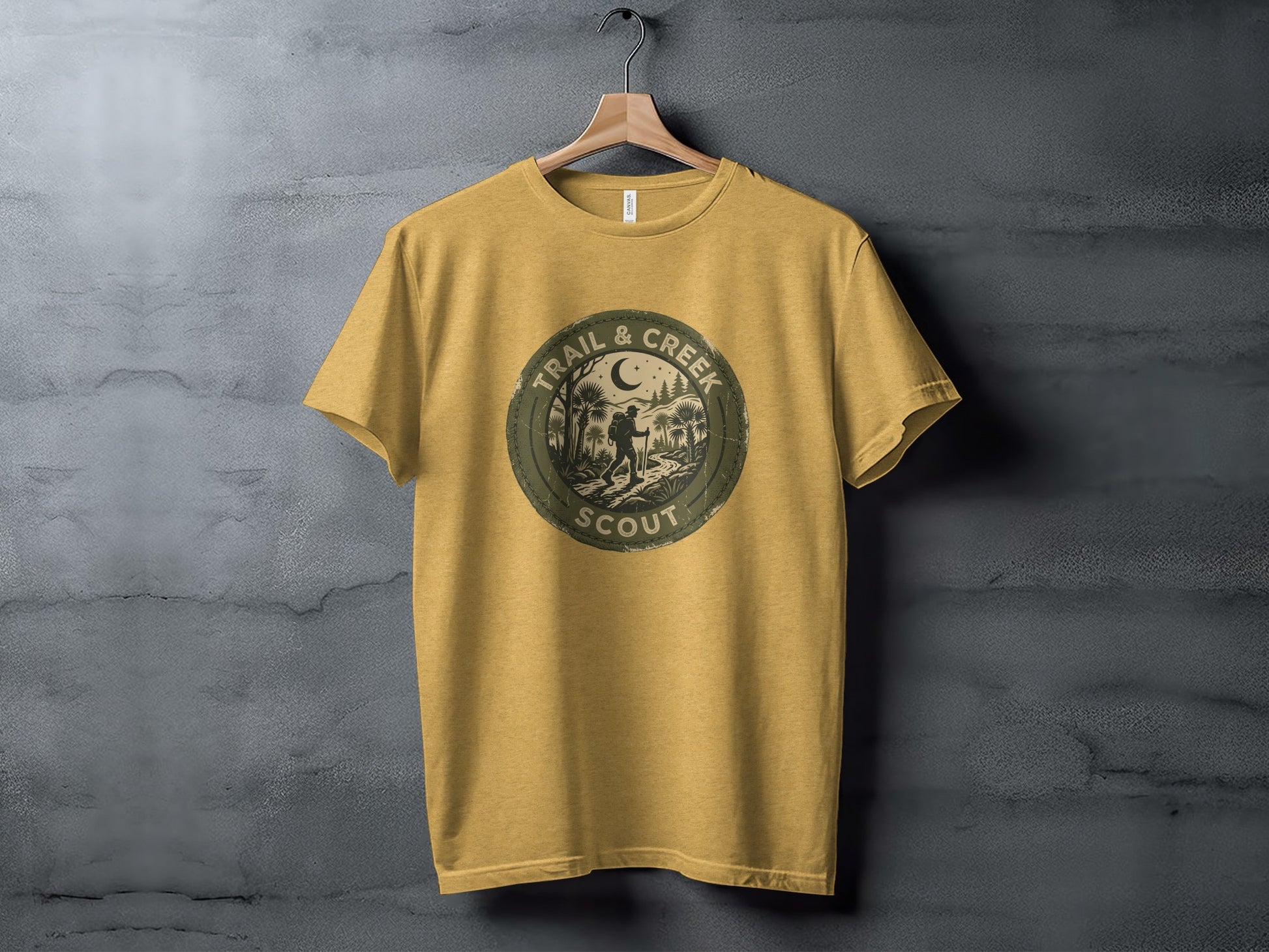 Heritage Trail & Creek Scout Adventure Nomad Tee: Mustard t-shirt with circular "Trail & Creek Scout" logo featuring a crescent moon and silhouette hikers.