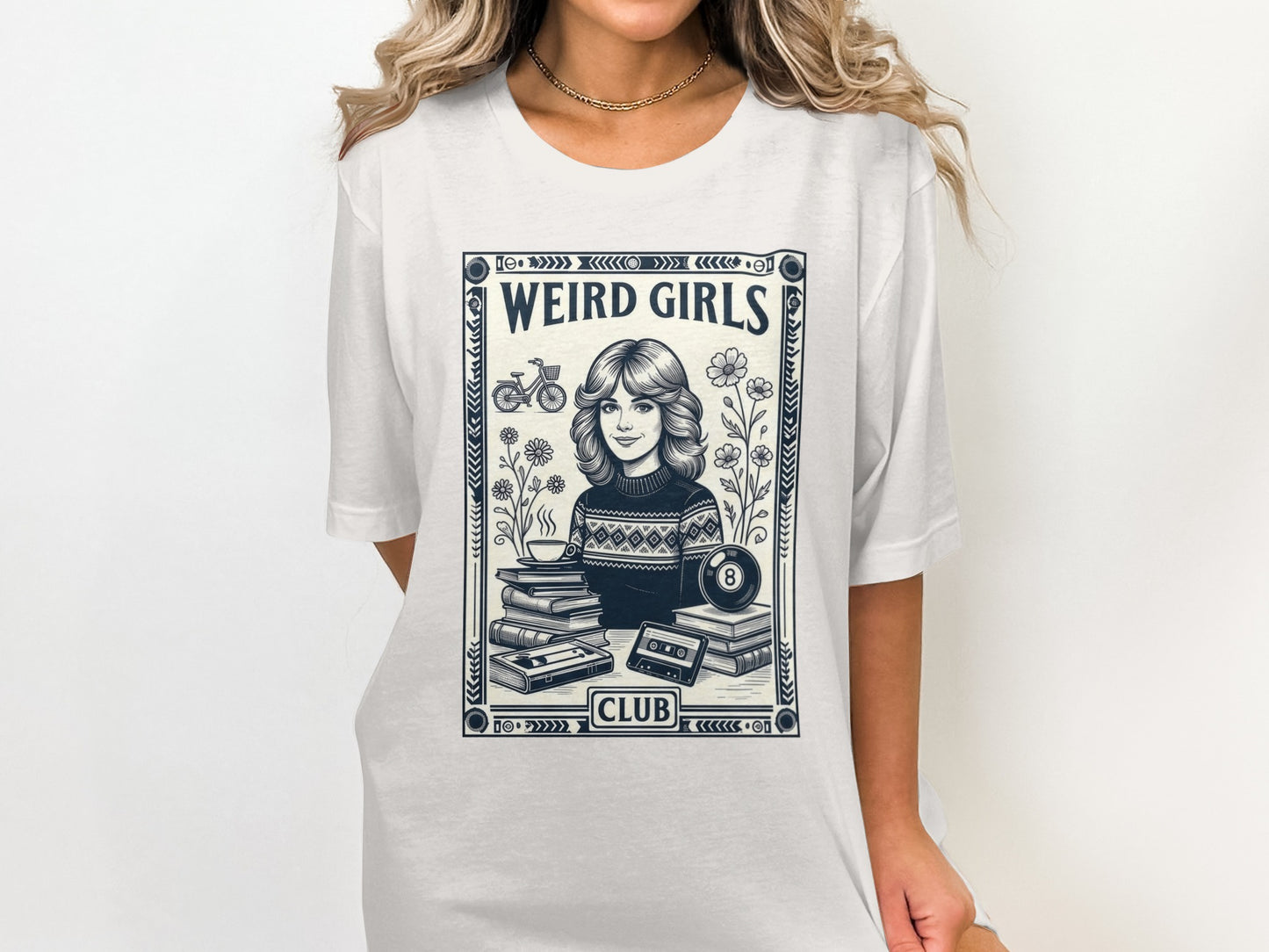 T-shirt graphic of a woman with flowers, books, and cassette tape labeled "Weird Girls Club".