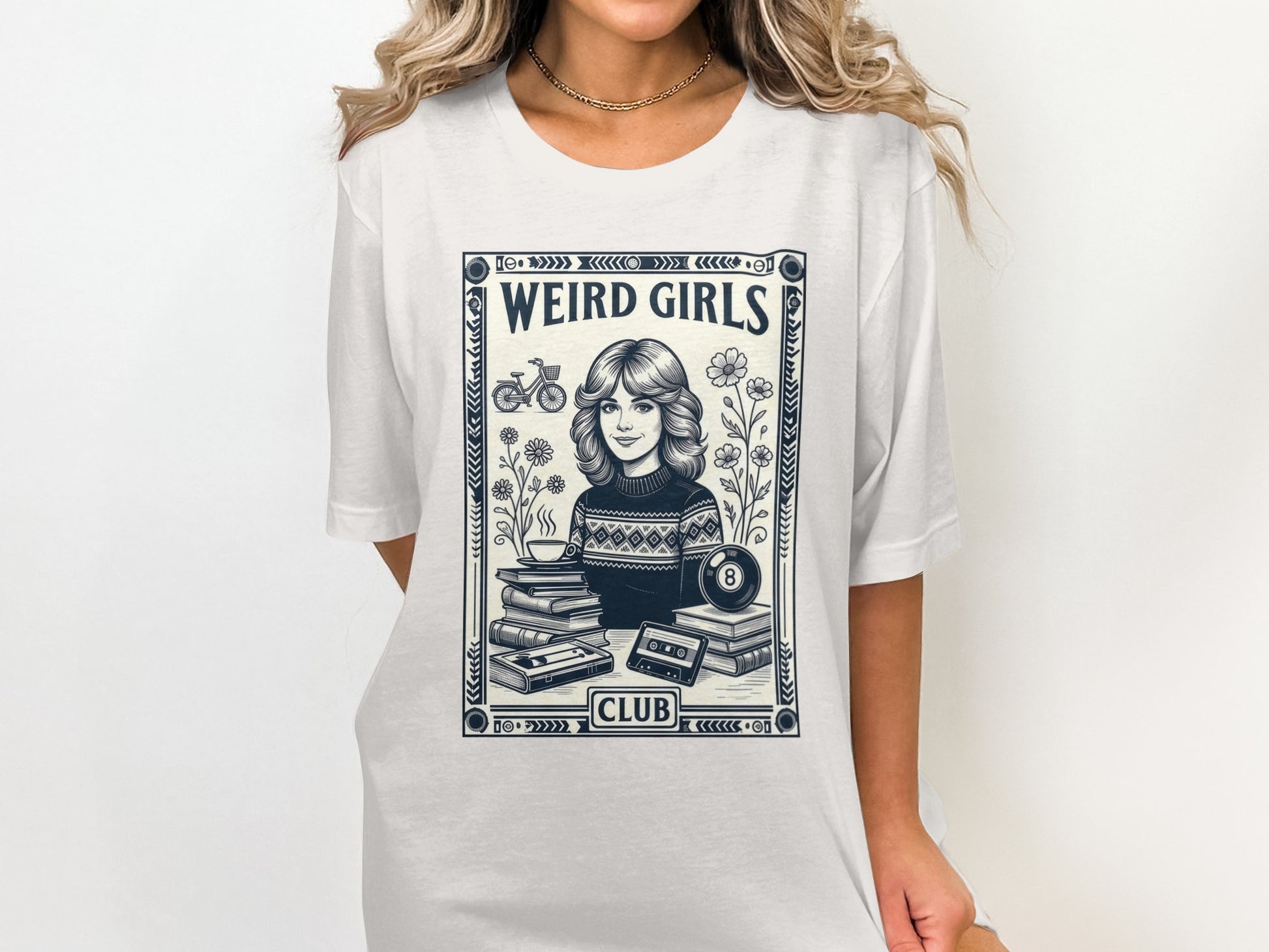 T-shirt graphic of a woman with flowers, books, and cassette tape labeled "Weird Girls Club".