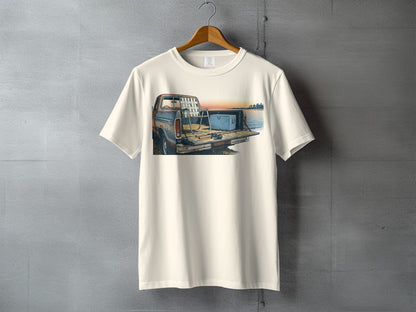 Cream t-shirt with illustration of a pickup truck bed with fishing gear at sunset.