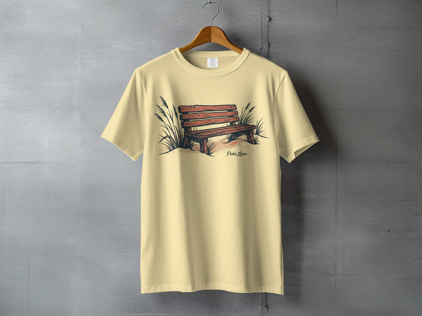 Light yellow t-shirt with a sketch of a wooden bench among beach grass.