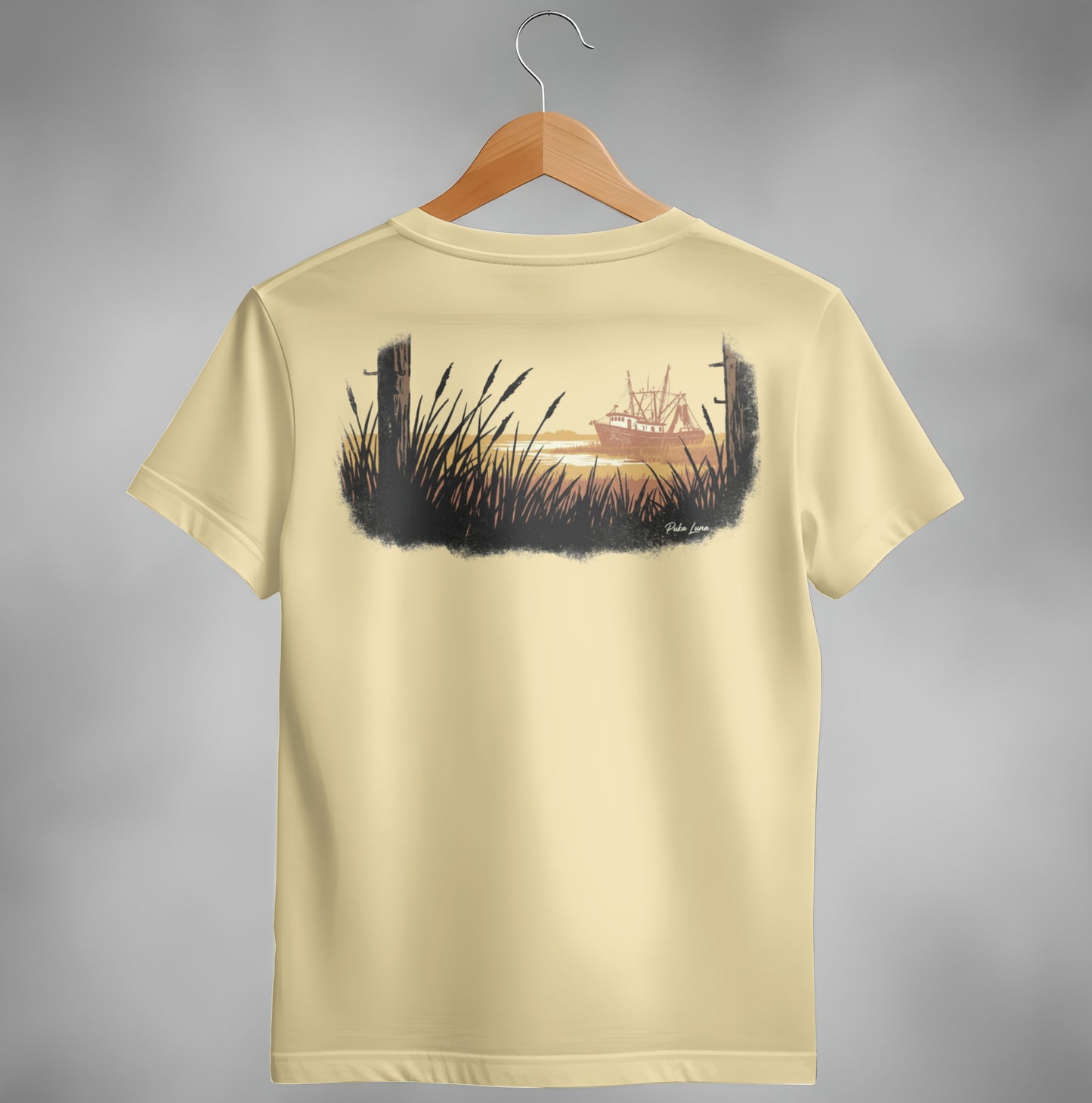 T-shirt with cream color and a graphic of a shrimp boat at sunset.
