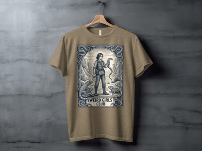 T-shirt graphic: woman holding snake, surrounded by lizards and snakes in ornate frame, "Weird Girls Club" text.