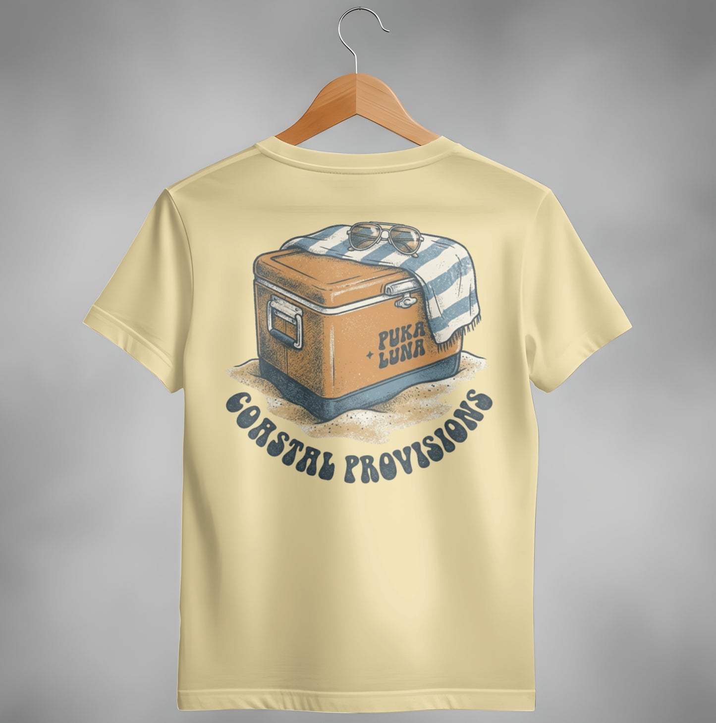 Cream t-shirt with graphic of a cooler, towel, and sunglasses on sand.