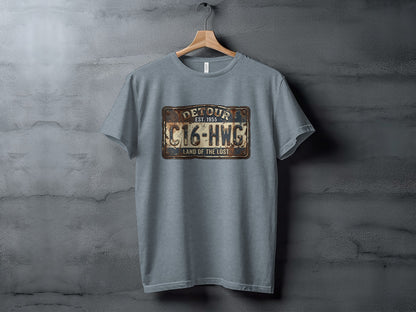 Land of the Lost Detour Plate: The Explorer's Adventure Tee: Grey t-shirt with "Detour Est. 1955 C16-HWG Land of the Lost" license plate graphic.