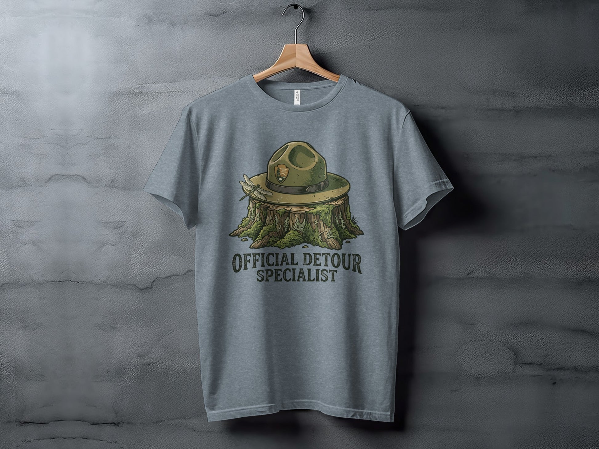 Official Detour Specialist Heritage | Vintage Outdoor Apparel: Grey t-shirt featuring a ranger hat on a tree stump with text "OFFICIAL DETOUR SPECIALIST".