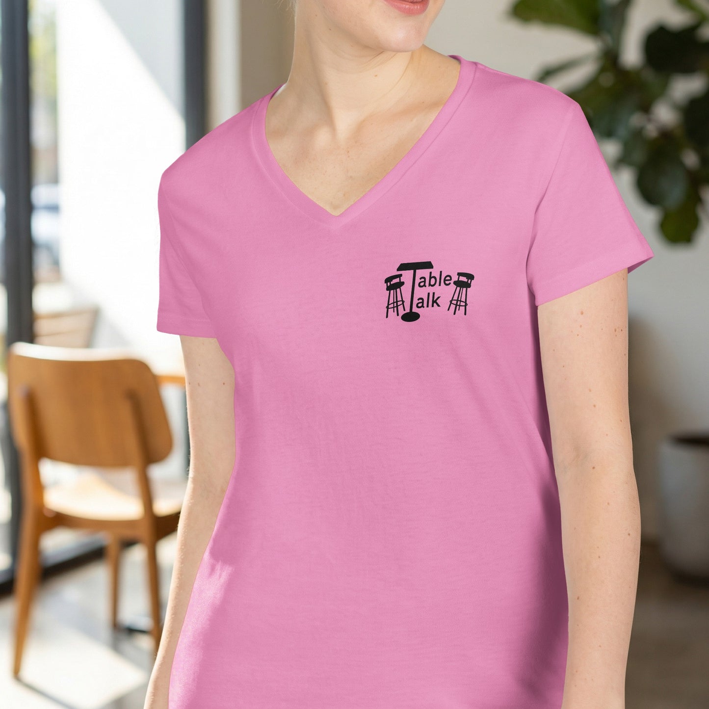 Pink v-neck t-shirt with "Table Talk" logo featuring a table and stools.