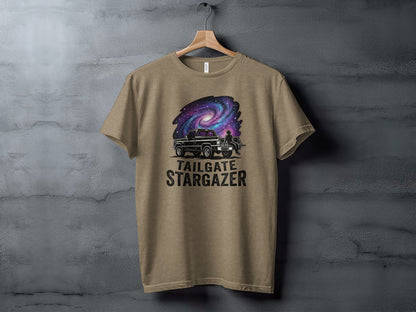 Heritage Cosmic Tailgate Stargazer Nomad Tee: Truck and galaxy design with "Tailgate Stargazer" text on a tan t-shirt.