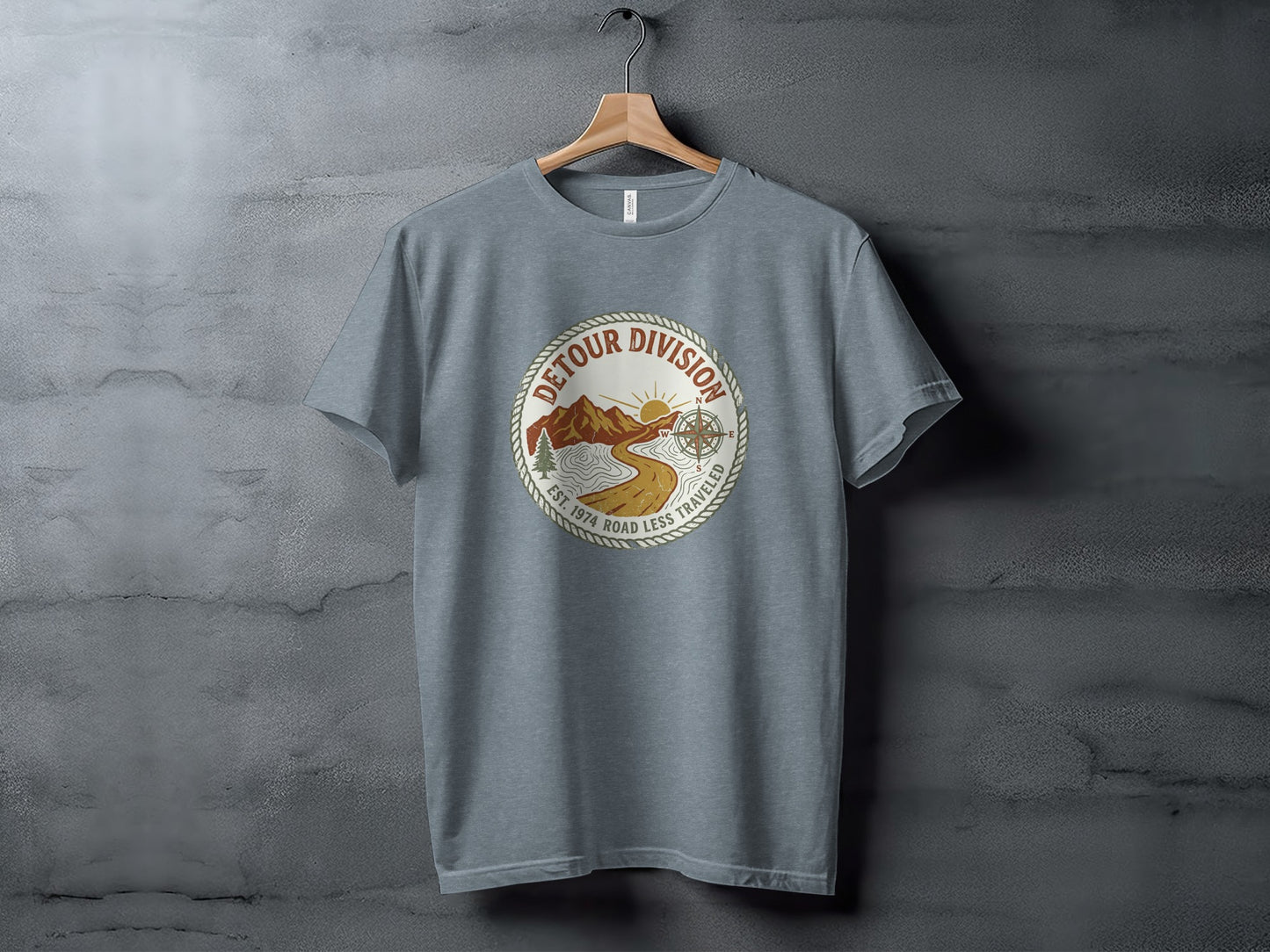 Detour Division Heritage | Vintage Outdoor Apparel: Gray t-shirt with a circular graphic featuring mountains, sun, and compass, "Detour Division Est. 1974 Road Less Traveled".