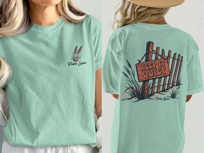 Mint green t-shirt with "Puka Luna" and grass graphic on front, "Keep It Quiet" sign on back.