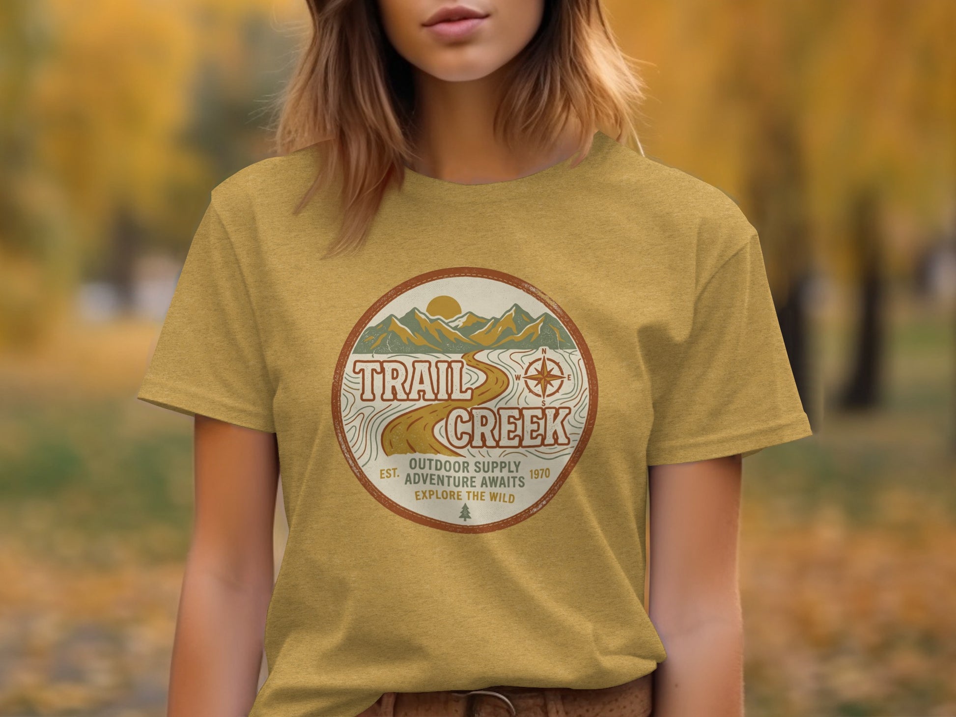 Heritage Heritage Explorer Trail Creek Nomad Tee: Gold t-shirt with "Trail Creek Outdoor Supply Adventure Awaits" circular graphic.