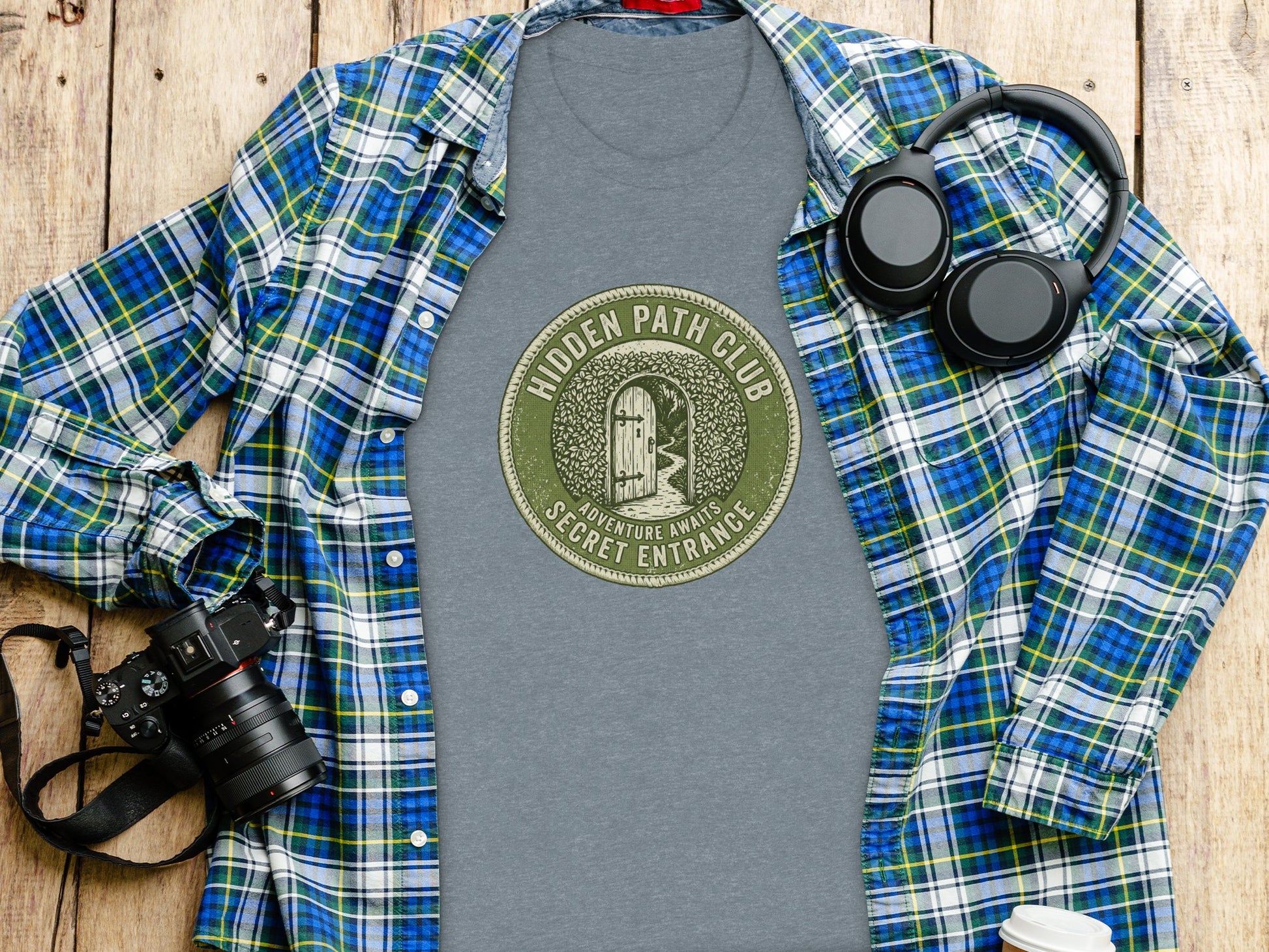 Hidden Path Club: Secret Entrance | Vintage Outdoor Apparel: Grey t-shirt with "Hidden Path Club" graphic, headphones, camera, and plaid shirt.