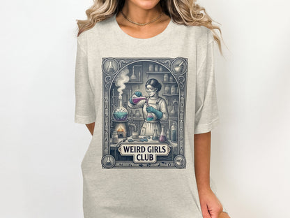 Graphic tee with woman in lab coat performing chemistry experiment, "Weird Girls Club" text.