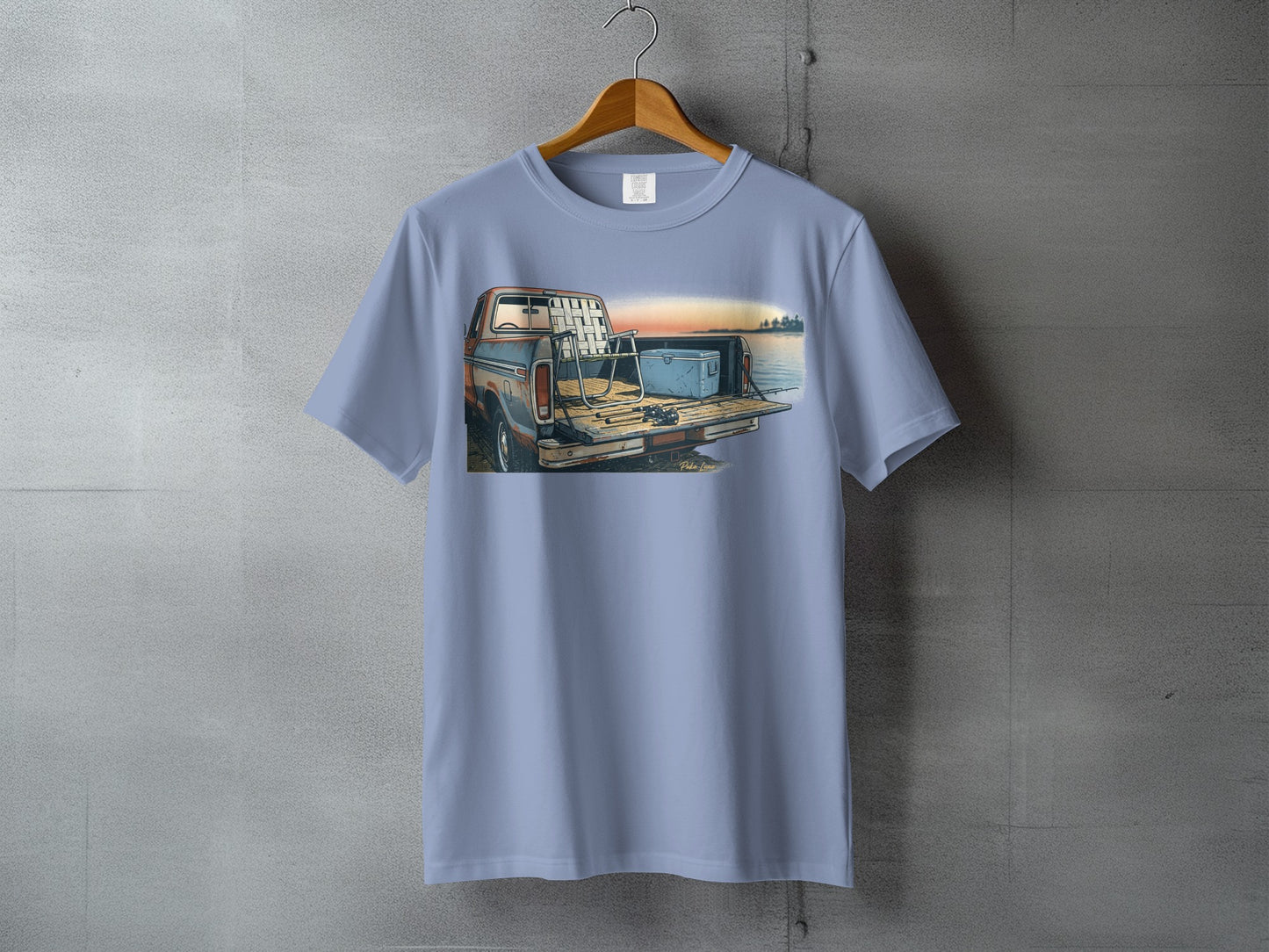 T-shirt with illustration of truck, fishing gear, and lake at sunset.