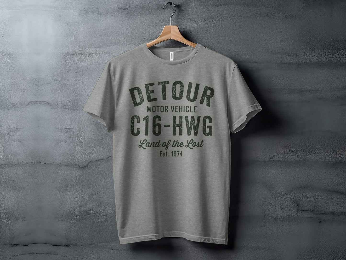Gray t-shirt with "DETOUR MOTOR VEHICLE C16-HWG Land of the Lost Est. 1974" printed on chest.
