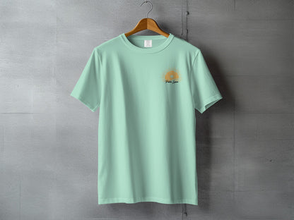 Mint green t-shirt with sun graphic and "Pura Vida" text, hanging on a hanger.