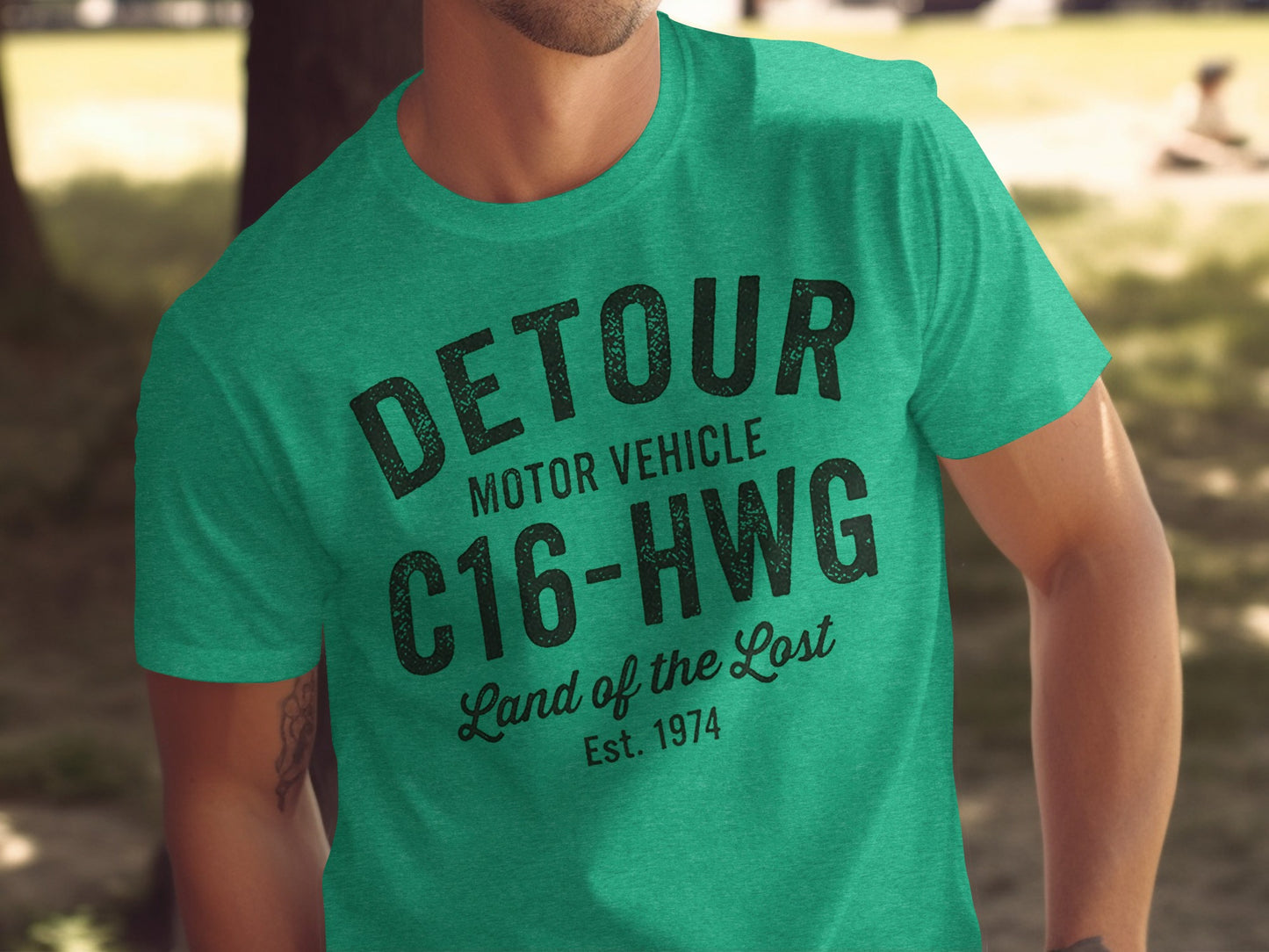 Green t-shirt with black "DETOUR MOTOR VEHICLE C16-HWG Land of the Lost Est. 1974" text.