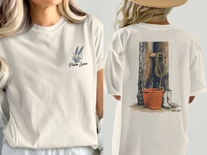 Cream t-shirt with wheat stalks on front, rustic wood and orange bucket on back.
