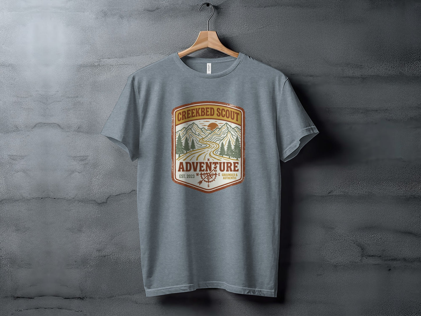 Rugged Creekbed Scout Adventure Emblem Wilderness Shirt: Grey t-shirt with Creekbed Scout Adventure logo featuring mountains, trees, and compass.