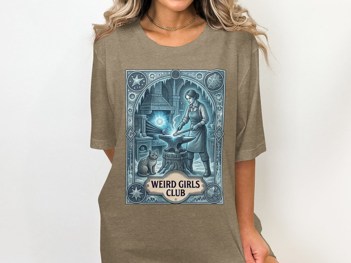 T-shirt graphic with an anvil, cat, and woman forging metal within an ornate border.