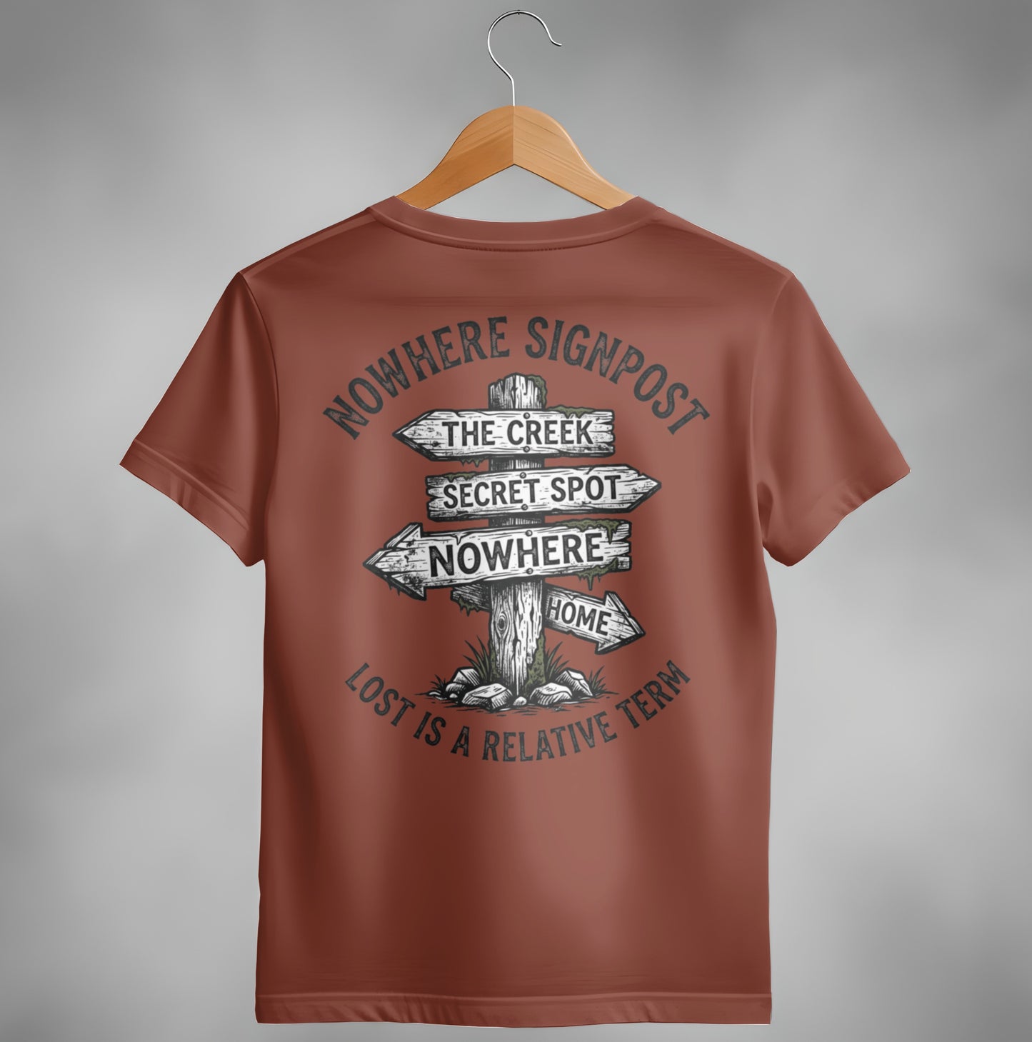 Brown t-shirt with a graphic of a wooden signpost pointing to "Nowhere," "The Creek," "Secret Spot," and "Home."