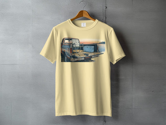 Cream t-shirt with illustration of a pickup truck bed with fishing gear by a lake.