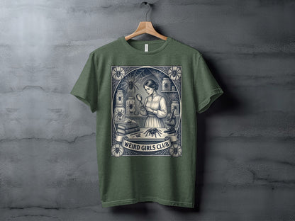 T-shirt with a vintage-style illustration of a woman examining a spider under a magnifying glass, text "WEIRD GIRLS CLUB".