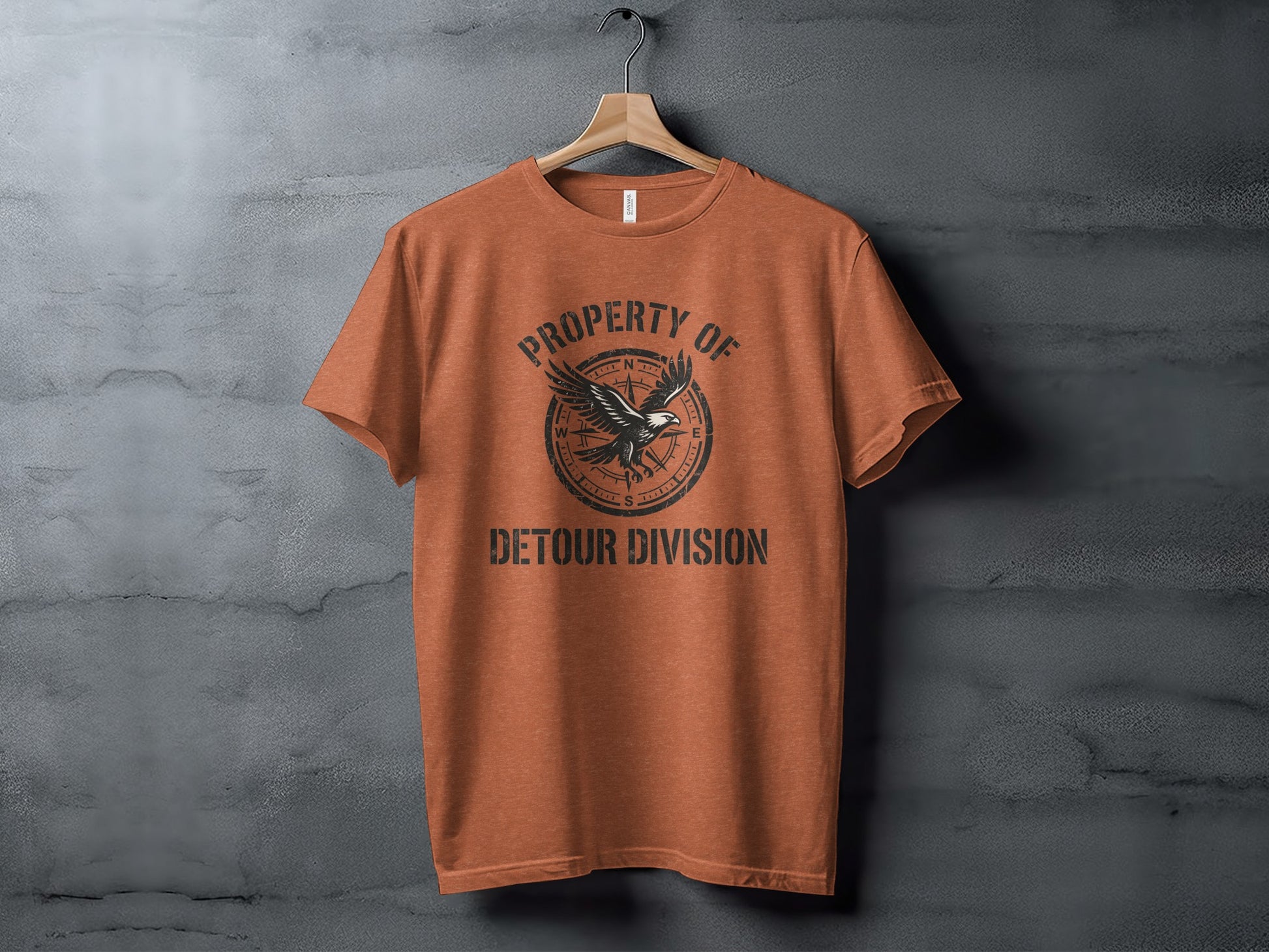 Rugged Detour Division Compass Eagle Tee Wilderness Shirt: Orange t-shirt with "PROPERTY OF DETOUR DIVISION" and compass design.