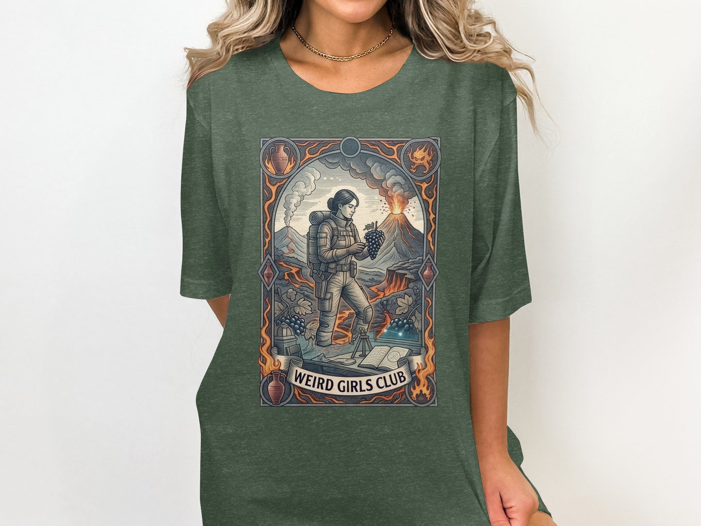 Woman wearing a green t-shirt with a graphic depicting a volcano, explorer, and grapes.
