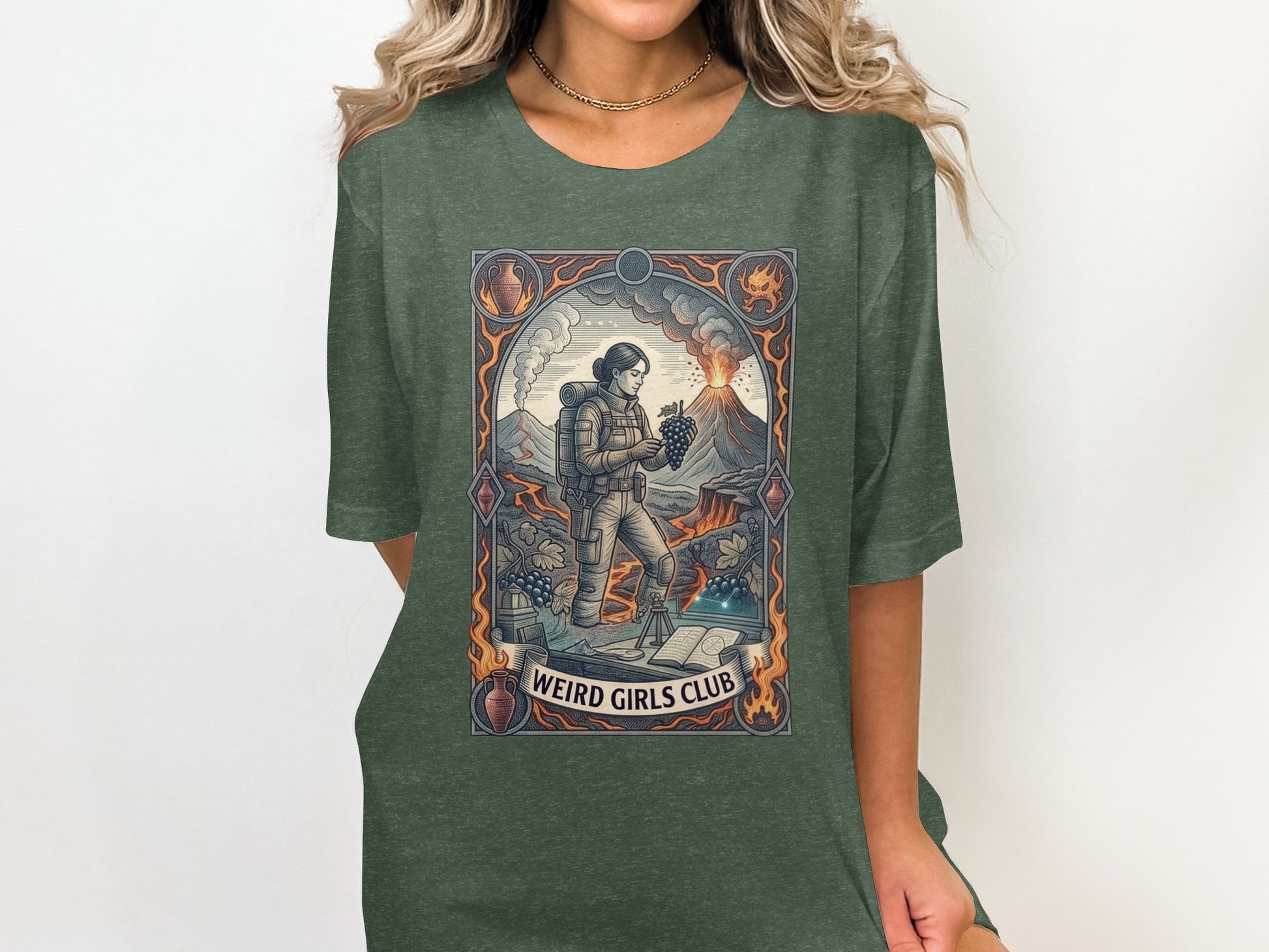 Woman wearing a green t-shirt with a graphic depicting a volcano, explorer, and grapes.