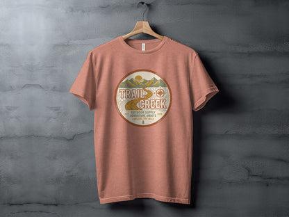 Heritage Heritage Explorer Trail Creek Nomad Tee: Coral t-shirt with circular nature graphic, "Trail Creek Outdoor Supply" text.