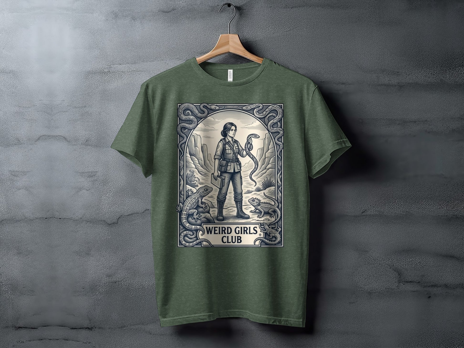 T-shirt graphic featuring a woman holding a snake surrounded by lizards and ornate border.