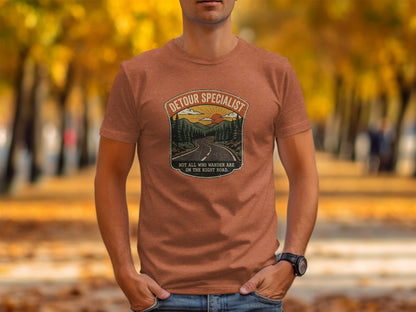 Heritage Detour Specialist Vintage Graphic Nomad Tee: Orange t-shirt with "DETOUR SPECIALIST" text and wilderness scene.