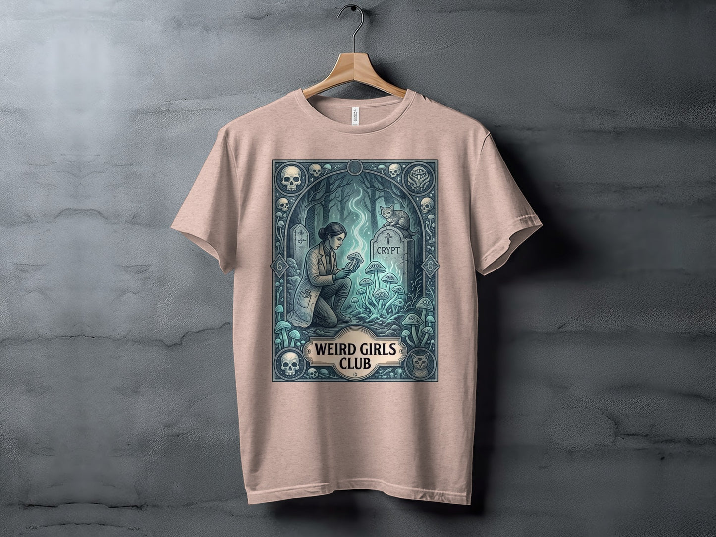 T-shirt featuring a gothic scene with mushrooms, skulls, a cat, and "Weird Girls Club" text.
