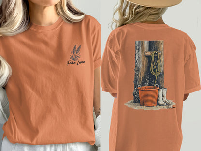 Orange t-shirt with wheat graphic on front and rope, bucket, and boots on back.