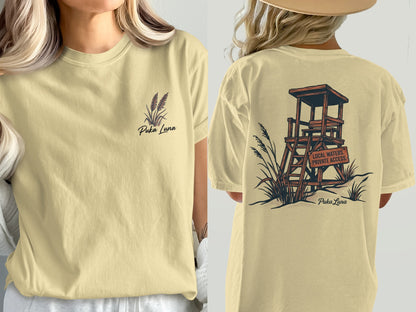 Pale yellow t-shirt with Puka Luna logo and beach lifeguard stand graphic.